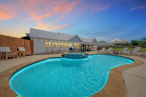A swimming pool with a sunken area, lounge chairs, and a building with large windows.