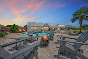 An outdoor seating area with Adirondack chairs, a fire pit, and a pool.