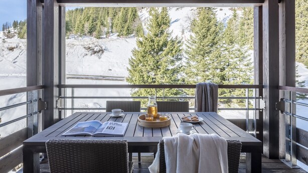 A wooden deck with a table set for breakfast, overlooking a snowy mountain landscape. - Apartment Near Ski Resort (Araches-la-Frasse)