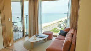 A modern living room with a large window overlooking a beach, a sofa, a small table, and a chair. - Cliffbeach Resort&Pool Villa (Yangyang)