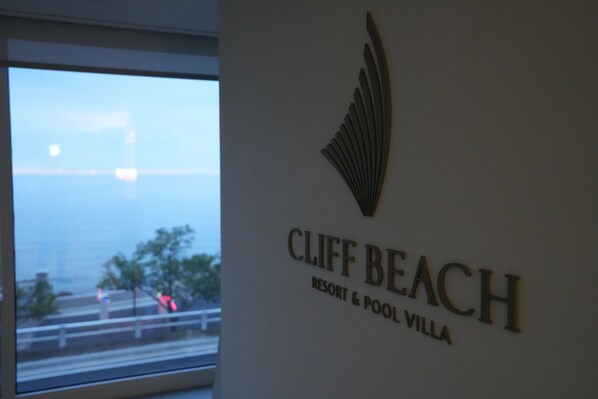 A sign for Cliff Beach Resort & Pool Villa with a view of the sea through a window. - Cliffbeach Resort&Pool Villa (Yangyang)