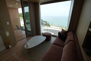 Una sala de estar moderna con un ventanal grande, un sofá, una mesa de centro y vistas al mar.
