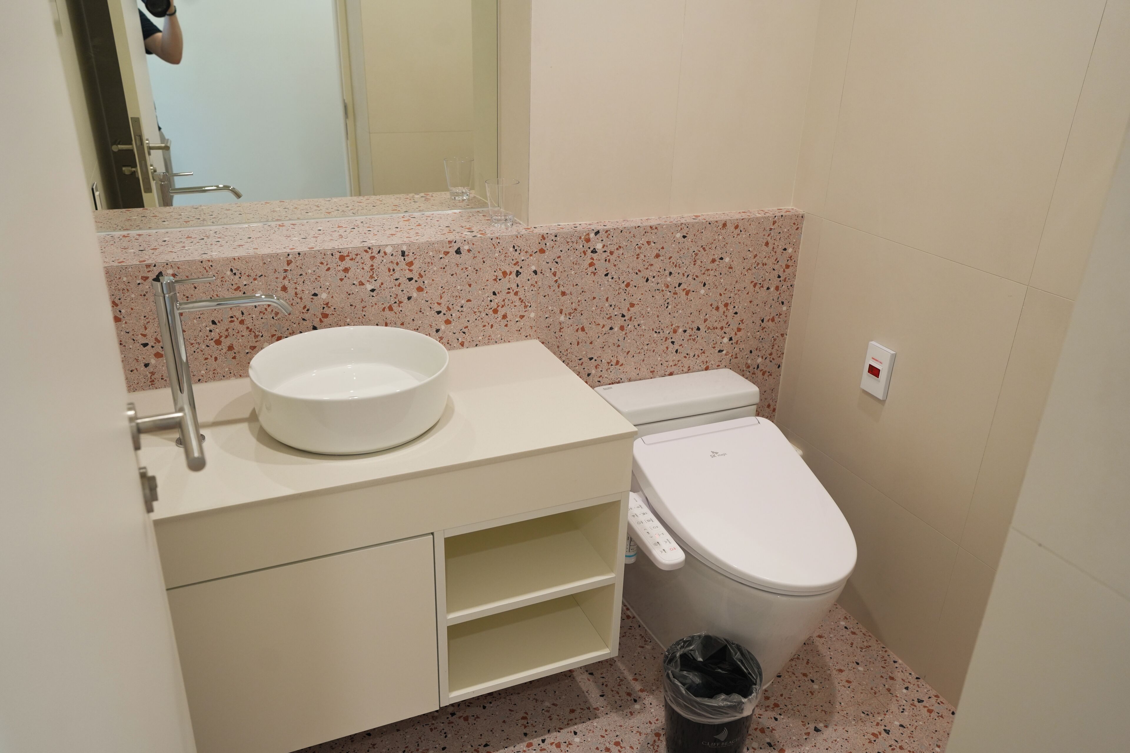 A bathroom with a white sink, a toilet, and a trash bin.