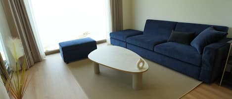 Una sala de estar con un sofá azul, una mesa de centro blanca y un tapete color beige.