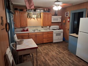A kitchen with wooden cabinets, a stove, a microwave, and a refrigerator.