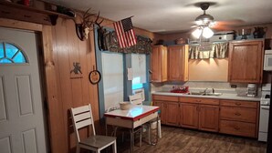A kitchen with wooden cabinets, a white countertop, a sink, and a ceiling fan. - Cabin 1 at the Lake, at Monterey Park an boat launch area (Zavalla)