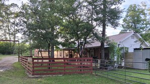 A fenced outdoor area with a building, trees, and a gravel path. - Cabin 1 at the Lake, at Monterey Park an boat launch area (Zavalla)