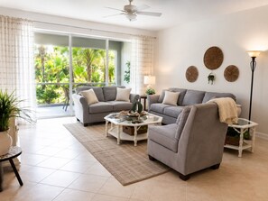 Ein Wohnzimmer mit zwei grauen Sofas, einem Glastisch und einer Stehlampe.