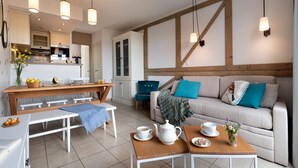 A modern living room with a sofa, a dining table, and a kitchen in the background. - Aesthetic Normandy House for 6 With Pool (Houlgate)