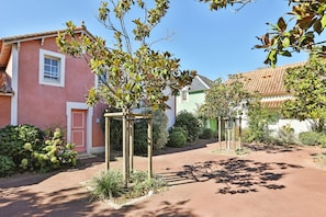 En asfalteret sti, der fører hen til en bygning med rosa facade og grøn d ør.