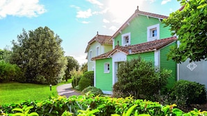 A green house with a tiled roof, surrounded by lush greenery and a clear sky. - Bourgenay Flat Near Coastal Slopes (Talmont-Saint-Hilaire)