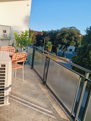 A balcony with a table and chairs, a railing, and a view of trees and buildings. - Aaron Guest House perfect for experiencing the city with comfort, style and convenience. (Venezia)