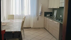 Uma cozinha com mesa de jantar, cadeiras, uma janela com cortinas e um ventilador de teto.