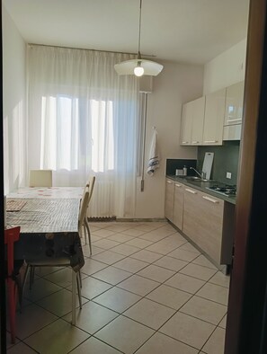 A kitchen with a dining table, chairs, a window with curtains, and a ceiling fan. - Aaron Guest House perfect for experiencing the city with comfort, style and convenience. (Venezia)