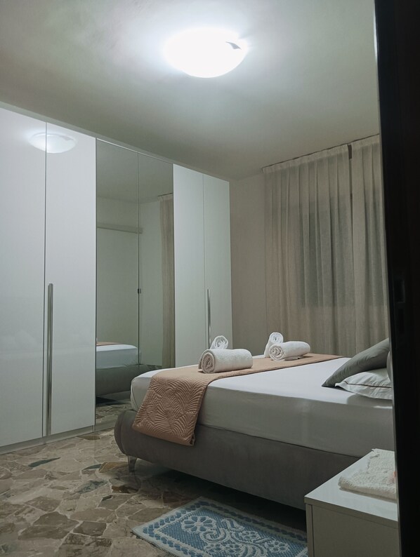 A bedroom with a bed, a wardrobe, a mirror, and a window with curtains. - Aaron Guest House perfect for experiencing the city with comfort, style and convenience. (Venezia)