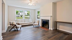 A living room with a white sofa, two armchairs, a fireplace, and a ceiling fan. - 3BR Augusta Retreat Near Medical, VA & Downtown (Augusta)