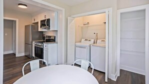 A compact kitchen with a refrigerator, stove, microwave, and a washing machine. - 3BR Augusta Retreat Near Medical, VA & Downtown (Augusta)