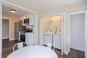 Eine kompakte Küche mit Kühlschrank, Herd, Mikrowelle und Waschmaschine.