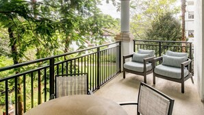 A balcony with a table and chairs, surrounded by greenery and a white building in the background. - Florida Holiday! 1 Bedroom, 1 Bath Villa - Marriott’s Lakeshore Reserve, Orlando (Orlando)