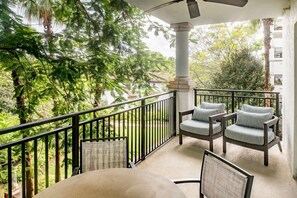 A balcony with a table and chairs, surrounded by greenery and a white building in the background. - Florida Holiday! 1 Bedroom, 1 Bath Villa - Marriott’s Lakeshore Reserve, Orlando (Orlando)
