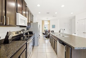 Eine moderne Küche mit dunklen Holzausziehtüren, Edelstahlgeräten und einer Arbeitsplatte aus Granit.