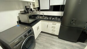 Eine moderne Küche mit einem Edelstahl-Kühlschrank, einer integrierten Waschmaschine und einer Kaffeemaschine.