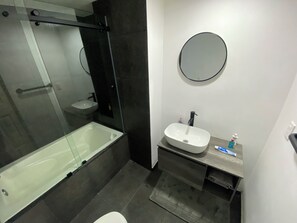 A modern bathroom with a glass-enclosed shower, a white sink, and a round mirror. - Beautiful apartment near Angel de la Independencia (Cuauhtémoc)