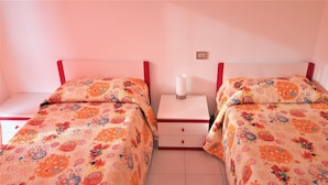 A bedroom with two beds, each with floral bedding, a bedside table with a lamp, and a small drawer unit. - Stunning Family Retreat Near Cinque Terre for 6 (Luni)