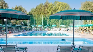 A swimming pool with multiple lounge chairs and umbrellas, surrounded by trees. - Stunning Family Retreat Near Cinque Terre for 6 (Luni)