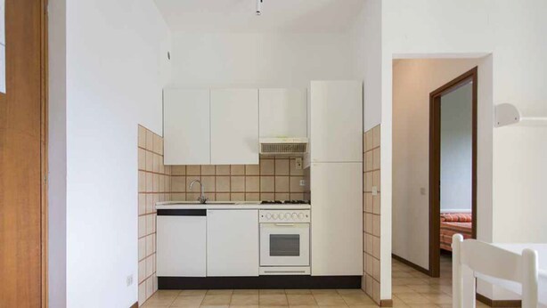 A compact kitchen with white cabinets, a stove, and a sink. - Stunning Family Retreat Near Cinque Terre for 6 (Luni)