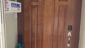 Eine Holztür mit Zahlenschloss, ein Briefkasten und eine Fußmatte.