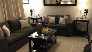 Ein Wohnzimmer mit zwei Sofas, einem Couchtisch, einem Beistelltisch und einem Spiegel an der Wand.