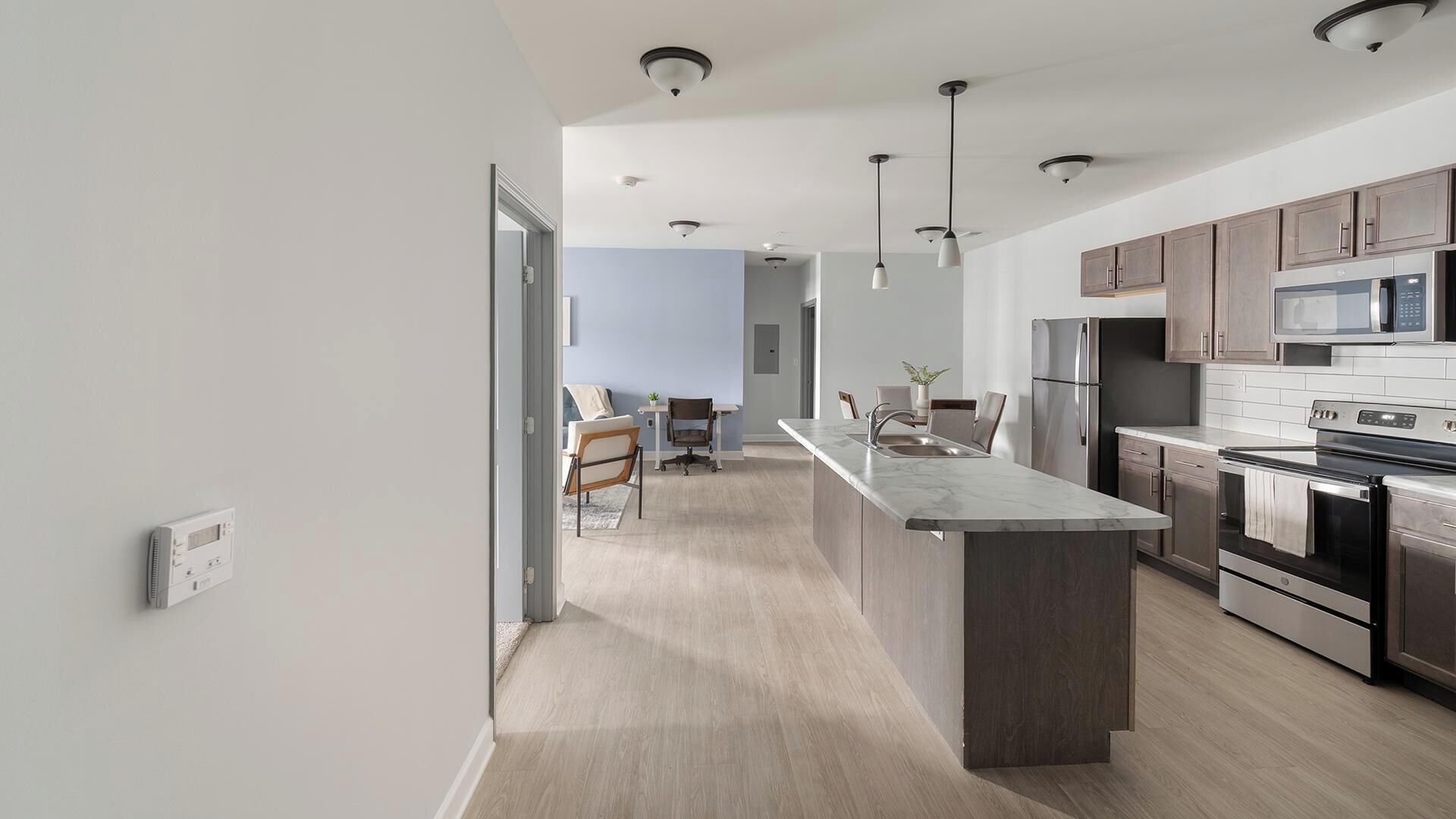 A modern kitchen with a central island, stainless steel appliances, and pendant lighting.