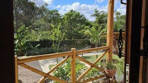 Un balcon en bois donnant sur un jardin et des arbres.