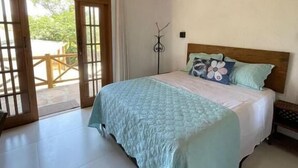 Une chambre à coucher avec un lit, un ventilateur de plafond, un plafond en bois et une vue à travers une porte vitrée.