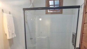 Une salle de bain avec une douche à parois de verre, des toilettes, un lavabo et une serviette accrochée au mur.