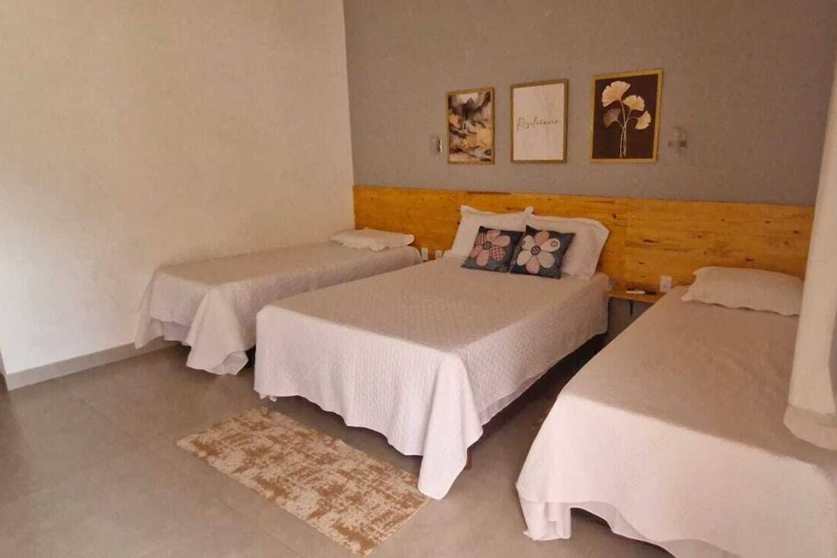 Una habitación con tres camas, un cabecero de madera y tres cuadros enmarcados en la pared.