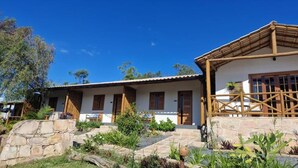 Un bâtiment à deux étages, à l’extérieur blanc, avec des fondations en pierre et une véranda couverte.