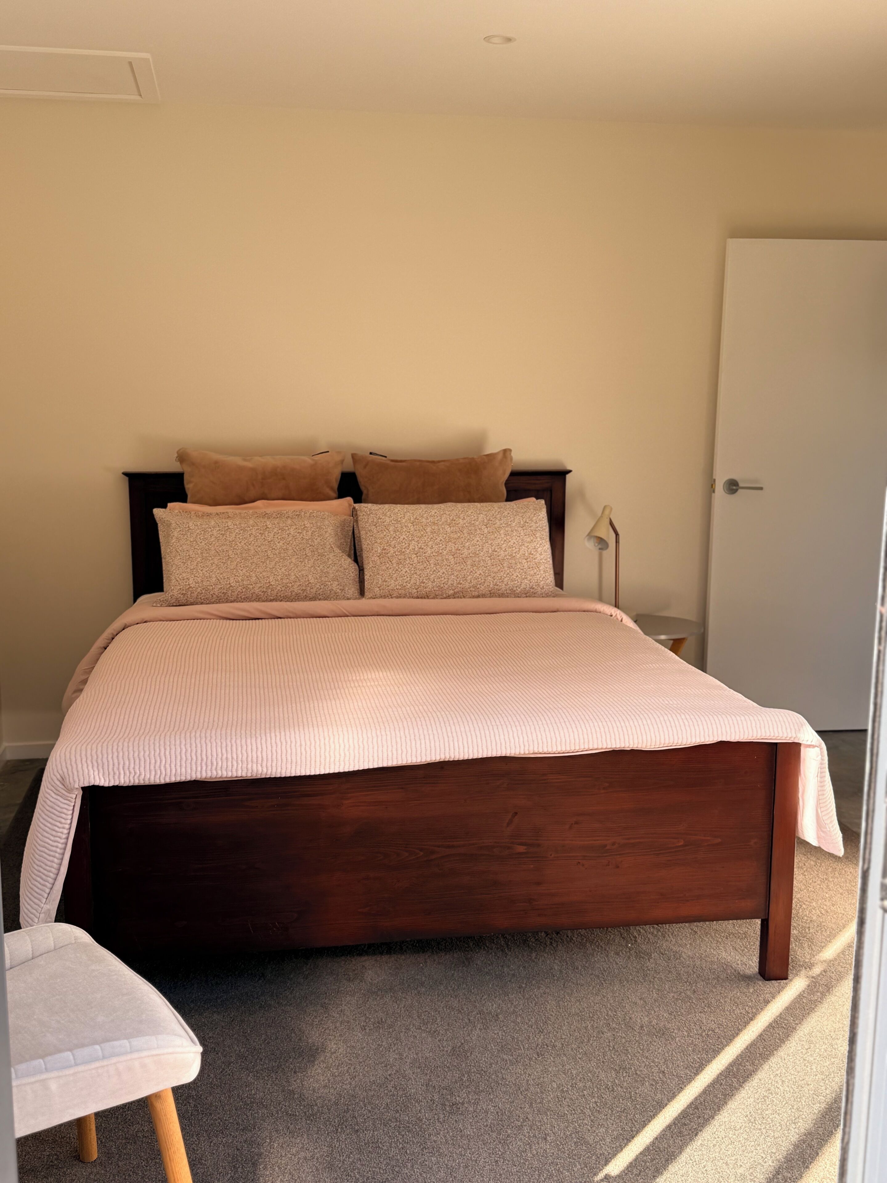 Un dormitorio con cama de madera, mesita de noche, lámpara y una puerta.