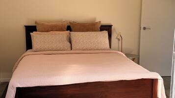 Un dormitorio con cama de madera, mesita de noche, lámpara y una puerta.