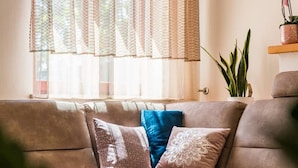 Ein Wohnzimmer mit einer Couch, einem Glastisch und einer Topfpflanze.