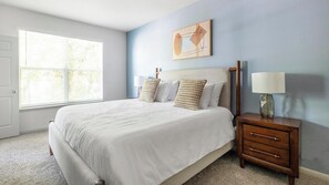 A bedroom with a bed, a nightstand, a lamp, a window, and a wall art piece. - Landing | Chic 2BD, Pool, Gym (Humble)