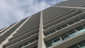 En høj bygning med moderne arkitektur, karakteriseret ved en række rektangulære vinduer og et markant, vertikalt element.