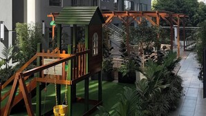 A children's play area with a swing set and a small house structure. - Tranquil 2-bedroom Apartment With Nature and City Views (Nairobi)