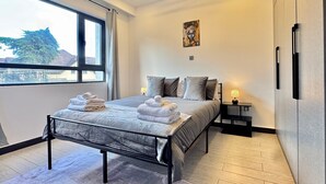 A modern bedroom with a bed, bedside tables, and a view of the outside. - Tranquil 2-bedroom Apartment With Nature and City Views (Nairobi)