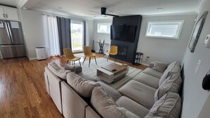 A modern living room with a sofa, chairs, a fireplace, and a kitchen area. - Near Everything, Seaside Hgts/Ortley Beach (Seaside Heights)