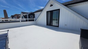 A rooftop terrace with a white railing, a glass door, and a clear blue sky. - Near Everything, Seaside Hgts/Ortley Beach (Seaside Heights)
