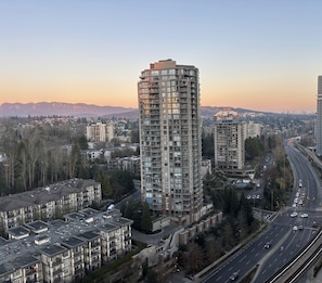 A high-rise building with multiple balconies, surrounded by other residential buildings and a highway.