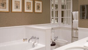 A bathroom with a bathtub, toilet, sink, and a window with a view. There are framed botanical prints on the wall. - Chewton Glen Hotel and Spa (New Milton)