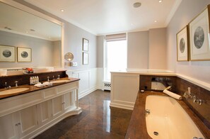 Ein geräumiges Badezimmer mit einer großen Badewanne, zwei Waschbecken und einem Schminktisch.